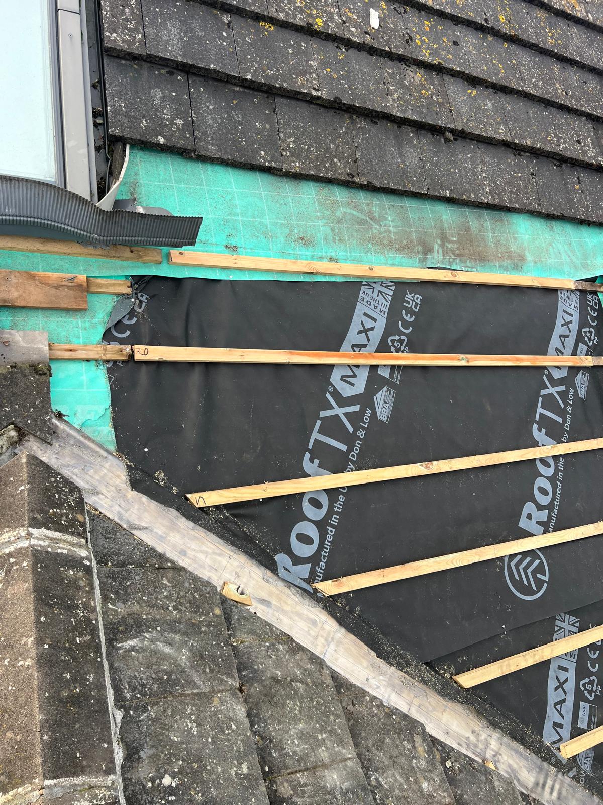 New blue breathable underlay (RoofTex brand) over new timber battens being laid on a stripped natural slate roof in Cumbria